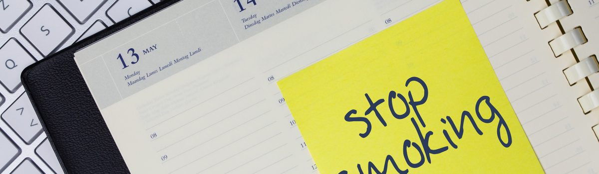 Werkplek met laptop en agenda waarin staat: stop smoking (stoppen met roken)