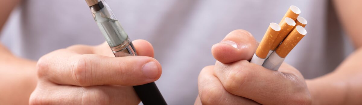 Twee handen met vape en sigaretten